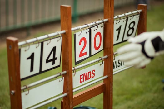 A close up shot of a lawn bowling scoreboard on grass, showing double digits.