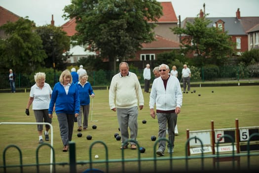 A front view shot of a group of senior friends walking off a bowling lawn.