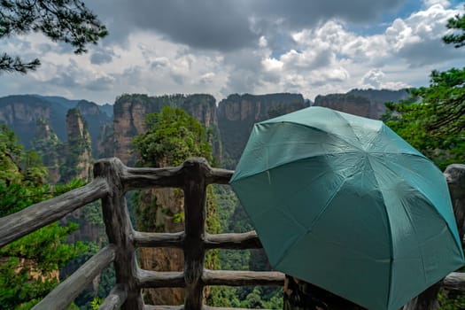 Tourist holding green umbrella admiring the view and  on the scenic viewpoint, Avatar mountains nature park, Zhangjiajie, China