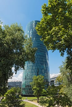 westhafen tower in frankfurt am main with trees in the front on a cloudy day