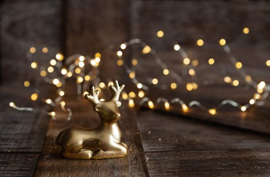 Golden Christmas ornament on wooden background with bokeh lights
