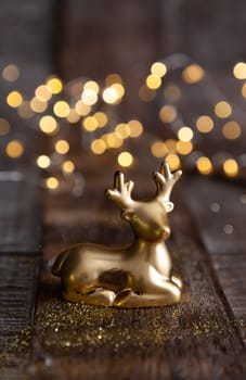 Golden Christmas ornament on wooden background with bokeh lights