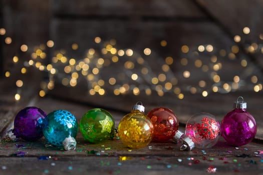 Colorful Christmas baubles on wooden background with bokeh lights