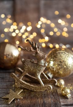 Golden Christmas ornaments on wooden background with bokeh lights
