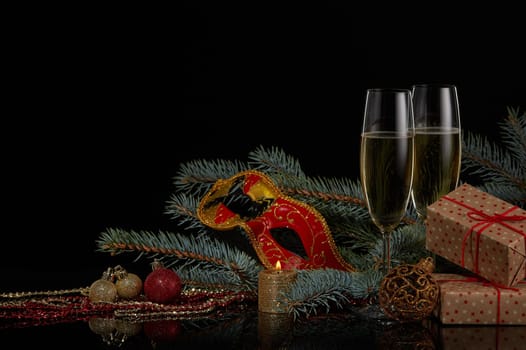 Still life with two wineglasses with champagne, gift boxes, fir tree branches and Christmas decorations on a black background. Copy space. New Year and Christmas