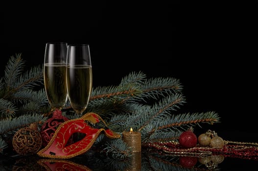 Still life with two wineglasses with champagne, fir tree branches and Christmas decorations on a black background. Copy space. New Year and Christmas