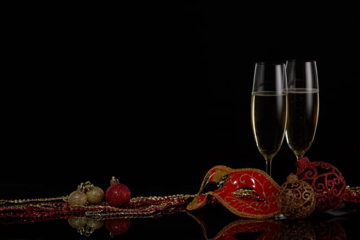 Two wineglasses with champagne and Christmas decorations on a black background. Copy space. New Year and Christmas