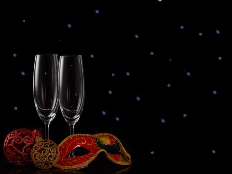 Two empty champagne flutes and Christmas decorations on a black background with LED lights garland. Copy space. New Year and Christmas