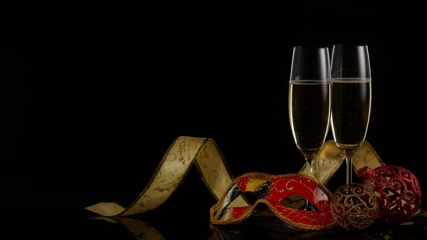 Two wineglasses with champagne and Christmas decorations on a black background. Copy space. New Year and Christmas