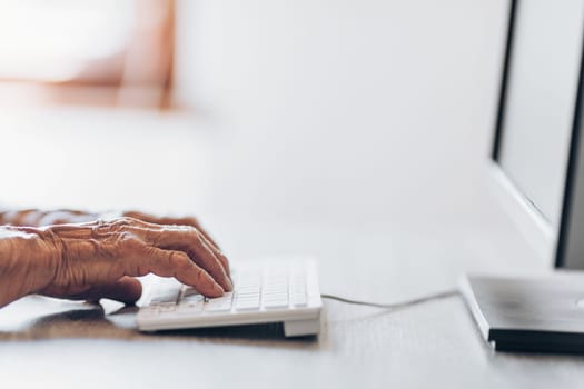 Elderly woman typing on a PC keyboard