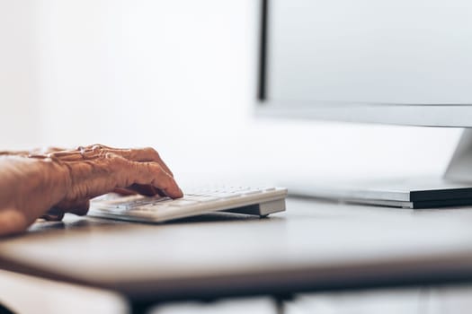 Elderly woman typing on a PC keyboard