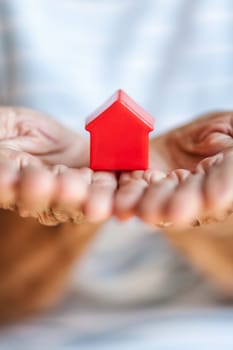 Elderly woman holding a small house in her hands