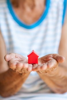 Elderly woman holding a small house in her hands