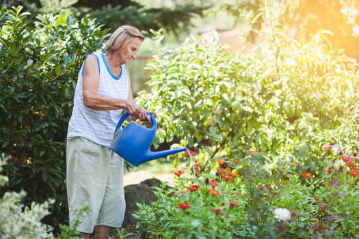 Elderly woman in her 80s watering plants in her garden