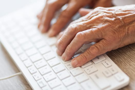 Elderly woman typing on a PC keyboard