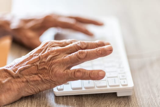 Elderly woman typing on a PC keyboard