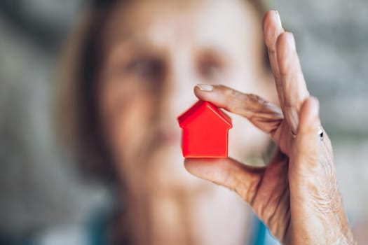 Elderly woman holding a small house in her hands