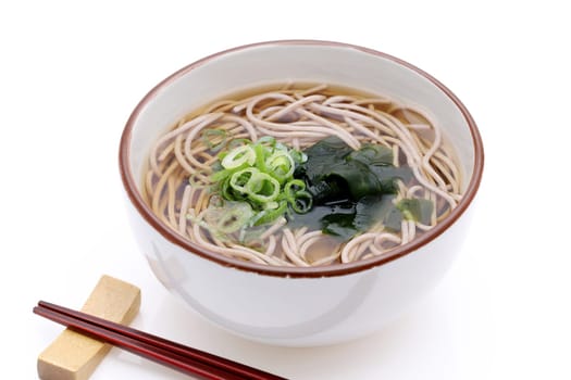 Japanese Kake soba noodles in a ceramic bowl on white background