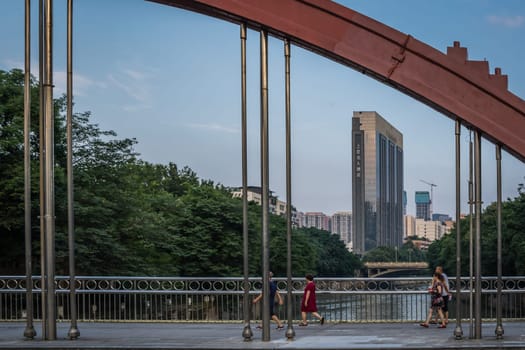Chengdu, China - July  2019 : People walking across the arched steel bridge in Chengdu city, Sichuan Province