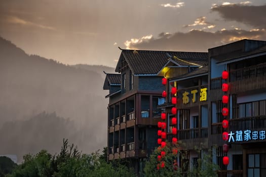 Wulingyuan, China -  August 2019 : Neons and facades of hotels, shops and restaurants during rainy sunset