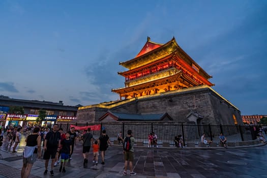 Xian, China -  July 2019 : Tourists walking in front of the Bell Drum Tower beautifully lit and illuminated at night, Shaaxi Province, Central China