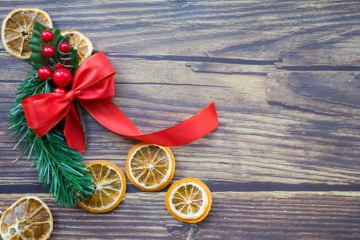 Christmas background from dried oranges, pine twig and red bow on a wooden table. Top view. Copyspace. Flatlay