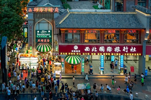 Xian, China -  July 2019 : Crowds walking among shops in the bustling streets of the Muslim Quarter in the evening as seen from the viewpoint in rum Tower, Xian city, Shaaxi Province