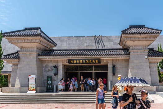 Xian, China -  July 2019 : Tourists walking on a path road leading to a museum site building containing Terracota Army sculptures, Xian, Shaanxi Province