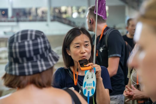 Xian, China -  July 2019 : China female tour guide talking to a mobile device so her group can hear her while visiting a museum, Xian, Shaanxi Province