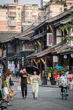 Chengdu, China -  July 2019 : Street scene in the city of Chengdu in summer, people walking on a street with old traditional chinese buildings in the background, Sichuan Province