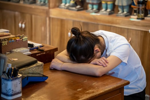 Xian, China -  July 2019 : Tired and exhausted from work and heat chinese girl sleeping at the desk in a souvenir shop