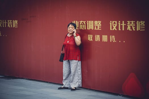 Chengdu, China -  July 2019 : Street scene in the city of Chengdu in summer, woman talking on her mobile phone, Sichuan Province