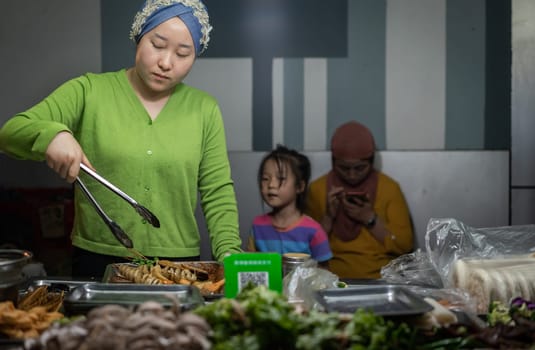 Xian, China -  August 2019 : Muslim woman selling snacks on the food street in the Muslim Quarter