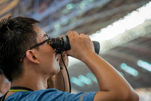 Xian, China -  July 2019 : Chinese tourist looking through the binoculars at the Terracota Army, Xian, Shaanxi Province