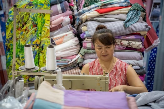 Chengdu, China -  July 2019 : Chinese woman uses electric sewing machine for sewing clothes in her textile shop