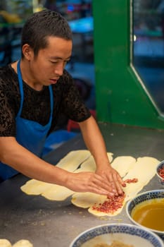 Xian, China -  August 2019 :  Man making minced beef meat filled pastries in a small local bakery on the street in Muslim Quarter, Xian town