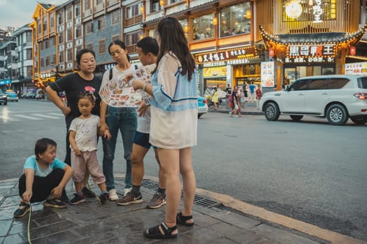 Wulingyuan, China - August 2019 : Chinese family standing outside restaurant and deliberating over menu