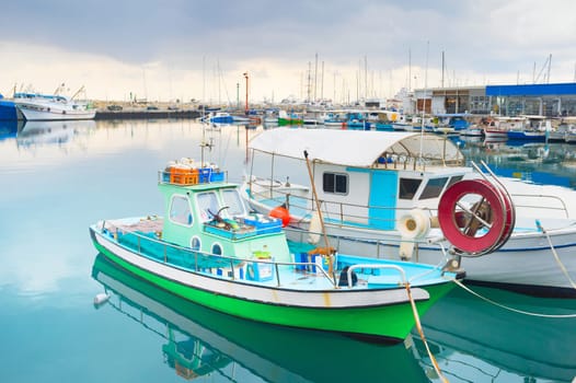 Colorful fishing boats moored in Limassol marina with restaurants on pier, Cyprus
