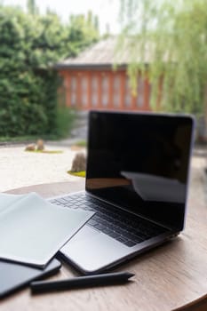 Modern laptop computer on wooden table in home garden, stock photo