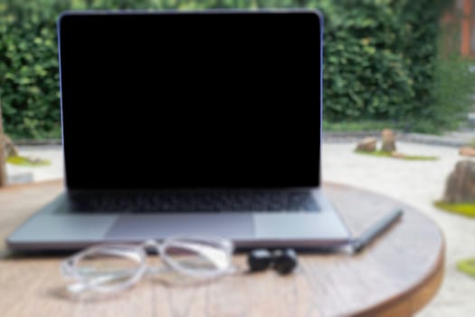 Modern laptop computer on wooden table in home garden, stock photo
