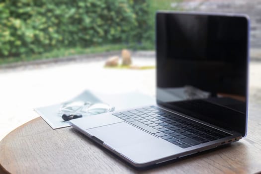 Modern laptop computer on wooden table in home garden, stock photo