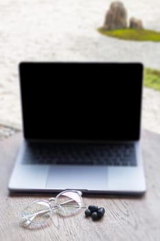 Modern laptop computer on wooden table in home garden, stock photo