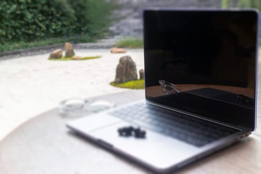 Modern laptop computer on wooden table in home garden, stock photo