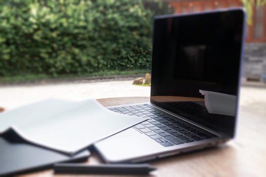 Modern laptop computer on wooden table in home garden, stock photo