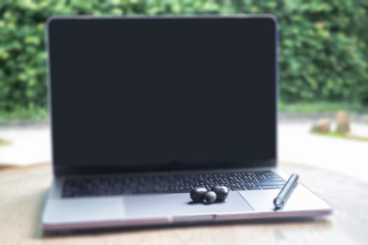 Modern laptop computer on wooden table in home garden, stock photo
