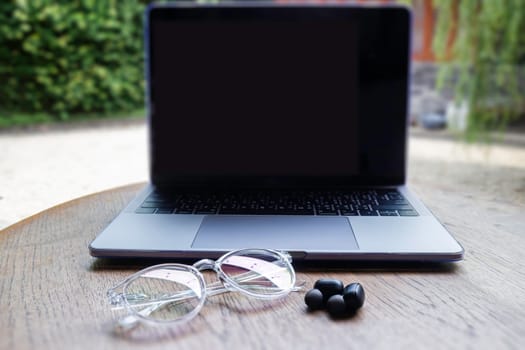 Modern laptop computer on wooden table in home garden, stock photo
