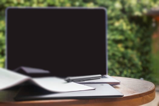 Modern laptop computer on wooden table in home garden, stock photo