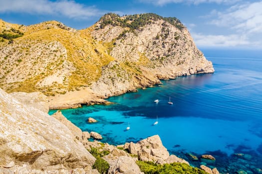 Beautiful coastline view of the cliffs with clear turquoise water and yachts. Cala Figuera beach on Cap de Formentor, Mallorca, Spain