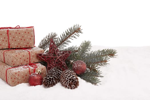 Christmas still life with gift boxes, fir tree branch and Christmas decorations lying on winter snow on a white background with copy space. New Year and Christmas. Greeting card