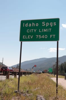 Idaho Springs, CO, USA - August 9, 2018: Looking East traveling Interstate 70 an Idaho Springs City Limit sign near a walkway. City limit elevation sign traveling I-70 into sunny Colorado in summer..